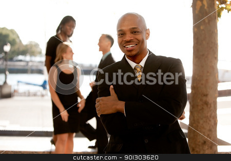 To use this stock image in your creative project, please select the size you need over to the right and click the "Add to Cart" button.
Your downloaded image will come with the Cutcaster watermark removed so don’t worry about the watermark you see on this page. Business Man stock photo, An african american business man with colleagues in the background by Tyler Olson