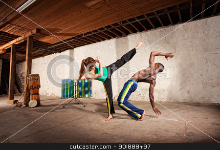 To use this stock image in your creative project, please select the size you need over to the right and click the "Add to Cart" button.
Your downloaded image will come with the Cutcaster watermark removed so don’t worry about the watermark you see on this page. Capoeria Sparring Practice with Drumming stock photo, Young Black man dodging a Capoeria kick with berimbau player in back by Scott Griessel