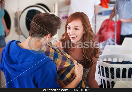 To use this stock image in your creative project, please select the size you need over to the right and click the "Add to Cart" button.
Your downloaded image will come with the Cutcaster watermark removed so don’t worry about the watermark you see on this page. Smiling Young Lady stock photo, Young lady smiles as a man holds a shirt in the laundromat by Scott Griessel