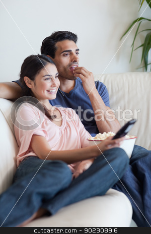 To use this stock image in your creative project, please select the size you need over to the right and click the "Add to Cart" button.
Your downloaded image will come with the Cutcaster watermark removed so don’t worry about the watermark you see on this page. Portrait of a couple watching TV while eating popcorn stock photo, Portrait of a couple watching TV while eating popcorn in their living room by Wavebreak Media
