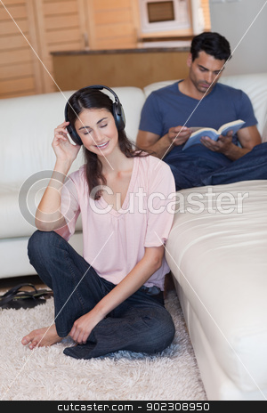 To use this stock image in your creative project, please select the size you need over to the right and click the "Add to Cart" button.
Your downloaded image will come with the Cutcaster watermark removed so don’t worry about the watermark you see on this page. Portrait of a woman listening to music while her fiance is readi stock photo, Portrait of a woman listening to music while her fiance is reading a book in their living room by Wavebreak Media