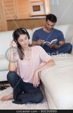 To use this stock image in your creative project, please select the size you need over to the right and click the "Add to Cart" button.
Your downloaded image will come with the Cutcaster watermark removed so don’t worry about the watermark you see on this page. Portrait of a woman listening to music while her boyfriend is re stock photo, Portrait of a woman listening to music while her boyfriend is reading a book in their living room by Wavebreak Media