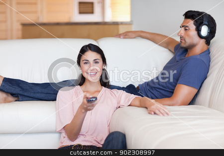 To use this stock image in your creative project, please select the size you need over to the right and click the "Add to Cart" button.
Your downloaded image will come with the Cutcaster watermark removed so don’t worry about the watermark you see on this page. Woman watching television while her husband is listening to musi stock photo, Woman watching television while her husband is listening to music in their living room by Wavebreak Media