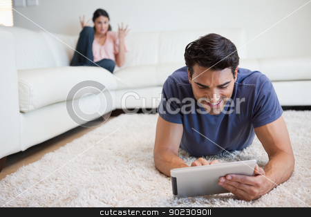 To use this stock image in your creative project, please select the size you need over to the right and click the "Add to Cart" button.
Your downloaded image will come with the Cutcaster watermark removed so don’t worry about the watermark you see on this page. Man using a tablet computer while his girlfriend is getting mad stock photo, Man using a tablet computer while his girlfriend is getting mad at him in their living room by Wavebreak Media