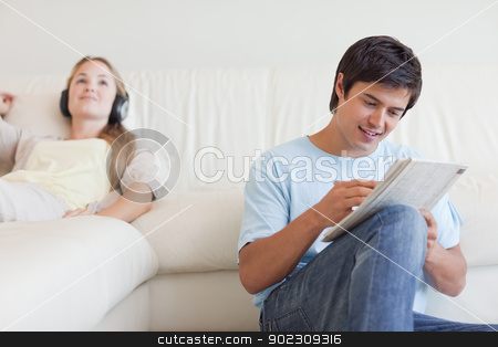 To use this stock image in your creative project, please select the size you need over to the right and click the "Add to Cart" button.
Your downloaded image will come with the Cutcaster watermark removed so don’t worry about the watermark you see on this page. Man doing crosswords while his fiance is listening to music stock photo, Man doing crosswords while his fiance is listening to music in their living room by Wavebreak Media