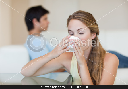 To use this stock image in your creative project, please select the size you need over to the right and click the "Add to Cart" button.
Your downloaded image will come with the Cutcaster watermark removed so don’t worry about the watermark you see on this page. Woman drinking tea while her fiance is sitting on a sofa stock photo, Woman drinking tea while her fiance is sitting on a sofa in their living room by Wavebreak Media