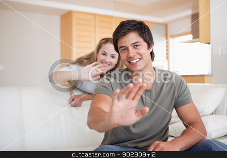To use this stock image in your creative project, please select the size you need over to the right and click the "Add to Cart" button.
Your downloaded image will come with the Cutcaster watermark removed so don’t worry about the watermark you see on this page. Couple waving at the camera stock photo, Couple waving at the camera in their living room by Wavebreak Media