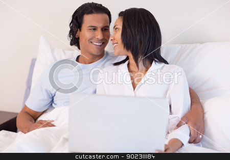 To use this stock image in your creative project, please select the size you need over to the right and click the "Add to Cart" button.
Your downloaded image will come with the Cutcaster watermark removed so don’t worry about the watermark you see on this page. Young couple sitting on the bed with their laptop stock photo, Smiling young couple sitting on the bed with their laptop by Wavebreak Media