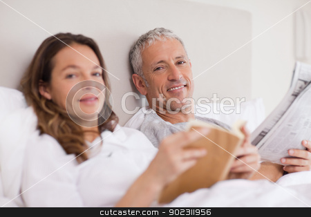To use this stock image in your creative project, please select the size you need over to the right and click the "Add to Cart" button.
Your downloaded image will come with the Cutcaster watermark removed so don’t worry about the watermark you see on this page. Happy woman reading a book while her husband is reading the news stock photo, Happy woman reading a book while her husband is reading the news in their bedroom by Wavebreak Media