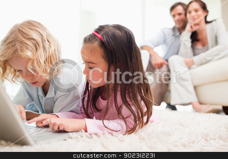 To use this stock image in your creative project, please select the size you need over to the right and click the "Add to Cart" button.
Your downloaded image will come with the Cutcaster watermark removed so don’t worry about the watermark you see on this page. Children using a notebook while their parents are in the backgro stock photo, Children using a notebook while their parents are in the background in a living room by Wavebreak Media