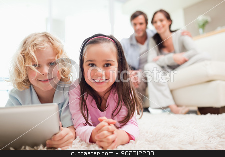 To use this stock image in your creative project, please select the size you need over to the right and click the "Add to Cart" button.
Your downloaded image will come with the Cutcaster watermark removed so don’t worry about the watermark you see on this page. Siblings using a tablet computer while their parents are in the stock photo, Siblings using a tablet computer while their parents are in the background in a living room by Wavebreak Media