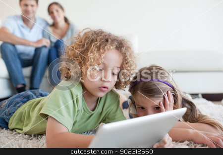To use this stock image in your creative project, please select the size you need over to the right and click the "Add to Cart" button.
Your downloaded image will come with the Cutcaster watermark removed so don’t worry about the watermark you see on this page. Young children using a tablet computer while their happy parents stock photo, Young children using a tablet computer while their happy parents are watching in their living room by Wavebreak Media