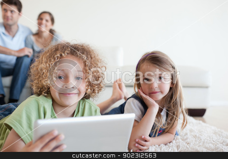 To use this stock image in your creative project, please select the size you need over to the right and click the "Add to Cart" button.
Your downloaded image will come with the Cutcaster watermark removed so don’t worry about the watermark you see on this page. Happy children using a tablet computer while their happy parents stock photo, Happy children using a tablet computer while their happy parents are watching in their living room by Wavebreak Media