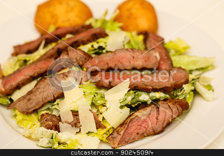 To use this stock image in your creative project, please select the size you need over to the right and click the "Add to Cart" button.
Your downloaded image will come with the Cutcaster watermark removed so don’t worry about the watermark you see on this page. Caesar Salad with Beef Strips and Rolls stock photo, A fresh caesar salad with strips of medium-rare beef and two muffins by Darryl Brooks