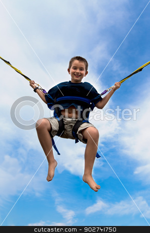 To use this stock image in your creative project, please select the size you need over to the right and click the "Add to Cart" button.
Your downloaded image will come with the Cutcaster watermark removed so don’t worry about the watermark you see on this page. Young boy swinging high in the air stock photo, Young boy swinging high in the air against a cloudy blue summer sky in a harness attached to cables or ropes with a beaming smile of enjoyment by Ozgur Coskun