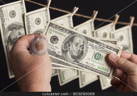 To use this stock image in your creative project, please select the size you need over to the right and click the "Add to Cart" button.
Your downloaded image will come with the Cutcaster watermark removed so don’t worry about the watermark you see on this page. Male Holding Hundred Dollar Bills, Many Handing from Clothesline stock photo, Male Hands Holding Hundred Dollar Bills with Several Hanging From a Clothesline on a Dark Background. by Andy Dean
