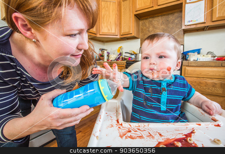 To use this stock image in your creative project, please select the size you need over to the right and click the "Add to Cart" button.
Your downloaded image will come with the Cutcaster watermark removed so don’t worry about the watermark you see on this page. Woman Feeds Baby stock photo, A woman in the kitchen feeds her baby from bottle by Scott Griessel