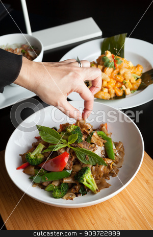 To use this stock image in your creative project, please select the size you need over to the right and click the "Add to Cart" button.
Your downloaded image will come with the Cutcaster watermark removed so don’t worry about the watermark you see on this page. Food Stylist stock photo, Food stylist grooms a dish by adding sweet basil garnish to the traditional thai dish Pad Kee Mao drunken noodle. by Todd Arena