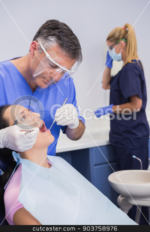 To use this stock image in your creative project, please select the size you need over to the right and click the "Add to Cart" button.
Your downloaded image will come with the Cutcaster watermark removed so don’t worry about the watermark you see on this page. Dentist wearing face shield and examining a patient stock photo, Dentist wearing face shield and examining a patient near his dental assistant by Wavebreak Media