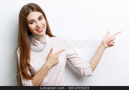 To use this stock image in your creative project, please select the size you need over to the right and click the "Add to Cart" button.
Your downloaded image will come with the Cutcaster watermark removed so don’t worry about the watermark you see on this page. Beautiful girl showing emotions stock photo, Portrait of a young beautiful girl with long brown hair wearing pink cotton blouse, standing waist up smiling and pointing with two hands to the left, on a white background by Zinkevych