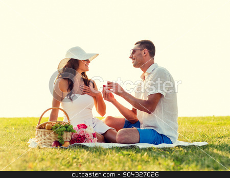 To use this stock image in your creative project, please select the size you need over to the right and click the "Add to Cart" button.
Your downloaded image will come with the Cutcaster watermark removed so don’t worry about the watermark you see on this page. smiling couple with small red gift box on picnic stock photo, love, dating, people and holidays concept - smiling young man showing small red gift box to his girlfriend on picnic by Syda Productions