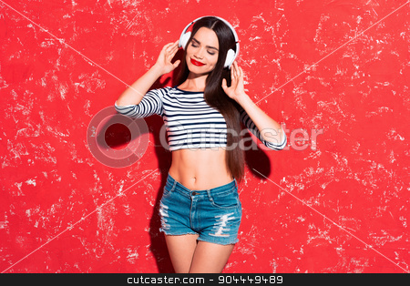 To use this stock image in your creative project, please select the size you need over to the right and click the "Add to Cart" button.
Your downloaded image will come with the Cutcaster watermark removed so don’t worry about the watermark you see on this page. Creative concept of beautiful sexy girl stock photo, Colorful picture of beautiful slim young woman with long hair on red background. Girl with headphones smiling and listening to music with her eyes closed by Dmytro Sidelnikov
