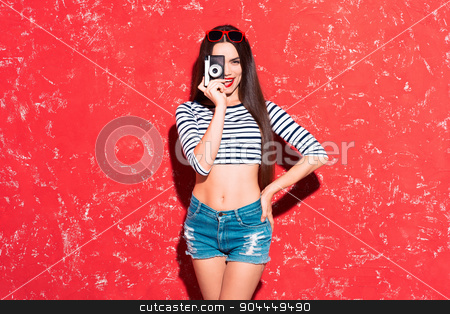 To use this stock image in your creative project, please select the size you need over to the right and click the "Add to Cart" button.
Your downloaded image will come with the Cutcaster watermark removed so don’t worry about the watermark you see on this page. Creative concept of beautiful sexy girl stock photo, Colorful picture of beautiful slim young woman with long hair on red background. Girl looking at camera, smiling and holding old fashioned camera by Dmytro Sidelnikov