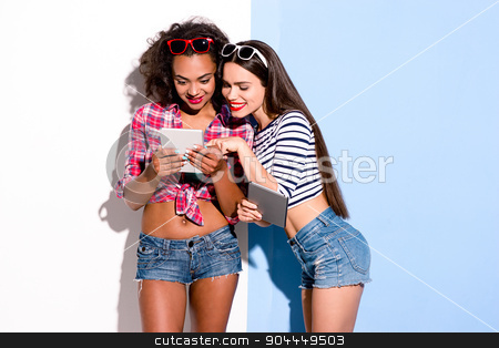 To use this stock image in your creative project, please select the size you need over to the right and click the "Add to Cart" button.
Your downloaded image will come with the Cutcaster watermark removed so don’t worry about the watermark you see on this page. Funky couple. Creative concept of beautiful sexy girls. stock photo, Colorful picture of beautiful slim young women on white and blue background. Girls smiling and looking at tablet computer by Dmytro Sidelnikov
