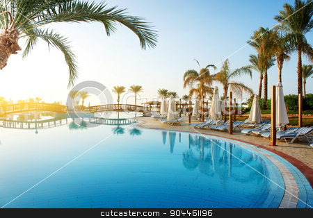 To use this stock image in your creative project, please select the size you need over to the right and click the "Add to Cart" button.
Your downloaded image will come with the Cutcaster watermark removed so don’t worry about the watermark you see on this page. Pool and palms stock photo, Swimming pool and big green palms at sunrise by Givaga