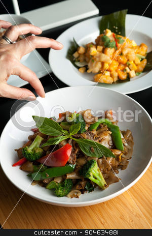 To use this stock image in your creative project, please select the size you need over to the right and click the "Add to Cart" button.
Your downloaded image will come with the Cutcaster watermark removed so don’t worry about the watermark you see on this page. Thai Food Stylist stock photo, Food stylist grooms a dish by adding sweet basil garnish to the traditional thai dish Pad Kee Mao drunken noodle. by Todd Arena