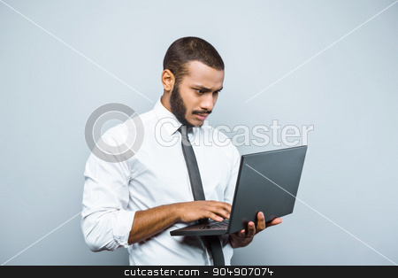 To use this stock image in your creative project, please select the size you need over to the right and click the "Add to Cart" button.
Your downloaded image will come with the Cutcaster watermark removed so don’t worry about the watermark you see on this page. Freestyle photo with young mulatto stock photo, Young mixed race businessman with beard standing on grey background. Young man using laptop by Dmytro Sidelnikov