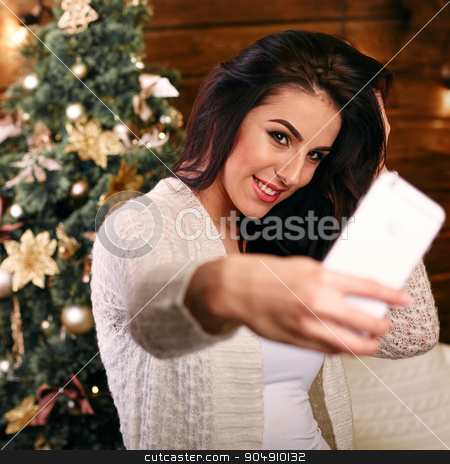 To use this stock image in your creative project, please select the size you need over to the right and click the "Add to Cart" button.
Your downloaded image will come with the Cutcaster watermark removed so don’t worry about the watermark you see on this page. people, holidays and technology concept - beautiful brunette woman in white sweater taking selfie picture by smartphone over christmas tree and living room background stock photo, people, holidays and technology concept - beautiful brunette woman in white Christmas sweater taking selfie picture by smartphone over christmas tree living room background by mykhalets
