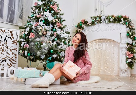 To use this stock image in your creative project, please select the size you need over to the right and click the "Add to Cart" button.
Your downloaded image will come with the Cutcaster watermark removed so don’t worry about the watermark you see on this page. Young woman near a Christmas tree holding gift box while sitting stock photo, Young beauty smiling santa woman near the Christmas tree. Fashionable luxury girl celebrating New Year. Beautiful luxury trendy brunette by mykhalets