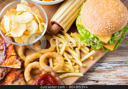 To use this stock image in your creative project, please select the size you need over to the right and click the "Add to Cart" button.
Your downloaded image will come with the Cutcaster watermark removed so don’t worry about the watermark you see on this page. close up of fast food snacks on wooden table stock photo, fast food and unhealthy eating concept - close up of hamburger or cheeseburger, deep-fried squid rings, french fries hotdog and potato chips on wooden table top view by Syda Productions