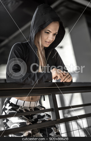 To use this stock image in your creative project, please select the size you need over to the right and click the "Add to Cart" button.
Your downloaded image will come with the Cutcaster watermark removed so don’t worry about the watermark you see on this page. Athletic girl posing in gym stock photo, Relaxed sportive girl leans on the railing in the gym. She looks in front of herself with a smile. Woman wears light pants with prints and a black top with a hooded jacket. Closeup. Vertica by bezikus