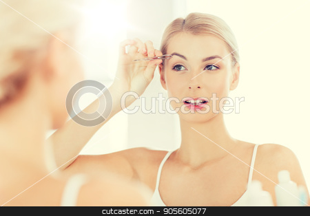To use this stock image in your creative project, please select the size you need over to the right and click the "Add to Cart" button.
Your downloaded image will come with the Cutcaster watermark removed so don’t worry about the watermark you see on this page. woman with tweezers tweezing eyebrow at bathroom stock photo, beauty and people concept - smiling young woman with tweezers tweezing eyebrow and looking to mirror at home bathroom by Syda Productions