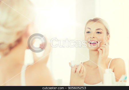 To use this stock image in your creative project, please select the size you need over to the right and click the "Add to Cart" button.
Your downloaded image will come with the Cutcaster watermark removed so don’t worry about the watermark you see on this page. happy woman applying cream to face at bathroom stock photo, beauty, skin care and people concept - smiling young woman applying cream to face and looking to mirror at home bathroom by Syda Productions