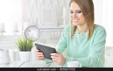 To use this stock image in your creative project, please select the size you need over to the right and click the "Add to Cart" button.
Your downloaded image will come with the Cutcaster watermark removed so don’t worry about the watermark you see on this page. Young woman looking at digital tablet stock photo, Beautiful young woman sitting at table and looking at digital tablet by Ruslan Huzau