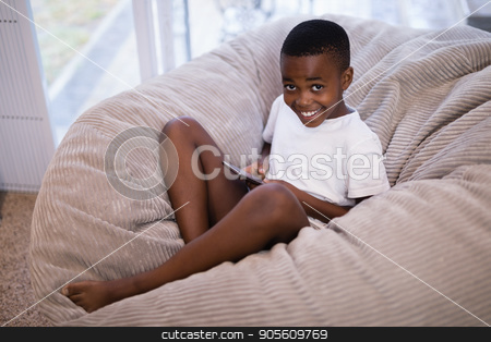 To use this stock image in your creative project, please select the size you need over to the right and click the "Add to Cart" button.
Your downloaded image will come with the Cutcaster watermark removed so don’t worry about the watermark you see on this page. Portrait of smiling boy using mobile phone while sitting on couch at home stock photo, High angle portrait of smiling boy using mobile phone while sitting on couch at home by Wavebreak Media