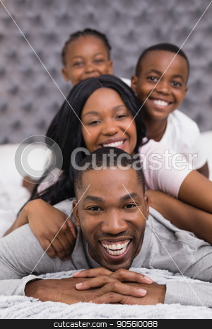 To use this stock image in your creative project, please select the size you need over to the right and click the "Add to Cart" button.
Your downloaded image will come with the Cutcaster watermark removed so don’t worry about the watermark you see on this page. Portrait of smiling man with family lying on bed stock photo, Portrait of smiling man with family lying together on bed at home by Wavebreak Media