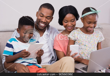 To use this stock image in your creative project, please select the size you need over to the right and click the "Add to Cart" button.
Your downloaded image will come with the Cutcaster watermark removed so don’t worry about the watermark you see on this page. Family using technologies while sitting on sofa at home stock photo, Happy family using technologies while sitting on sofa at home by Wavebreak Media