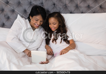 To use this stock image in your creative project, please select the size you need over to the right and click the "Add to Cart" button.
Your downloaded image will come with the Cutcaster watermark removed so don’t worry about the watermark you see on this page. High angle view of smiling grandmother and granddaughter using digital tablet on bed stock photo, High angle view of smiling grandmother and granddaughter using digital tablet on bed at home by Wavebreak Media