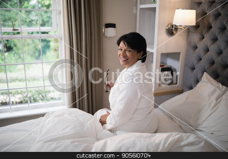 To use this stock image in your creative project, please select the size you need over to the right and click the "Add to Cart" button.
Your downloaded image will come with the Cutcaster watermark removed so don’t worry about the watermark you see on this page. Smiling mature woman sitting in illuminated bedroom at home stock photo, Portrait of smiling mature woman sitting in illuminated bedroom at home by Wavebreak Media