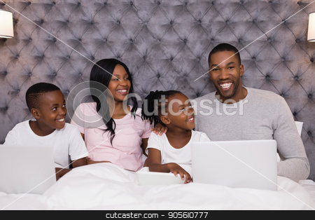 To use this stock image in your creative project, please select the size you need over to the right and click the "Add to Cart" button.
Your downloaded image will come with the Cutcaster watermark removed so don’t worry about the watermark you see on this page. Portrait of smiling man using laptop while sitting with family on bed stock photo, Portrait of smiling man using laptop while sitting with family on bed in bedroom at home by Wavebreak Media