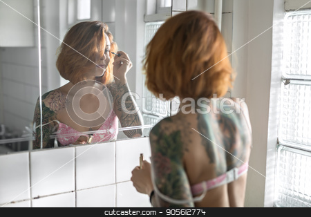 To use this stock image in your creative project, please select the size you need over to the right and click the "Add to Cart" button.
Your downloaded image will come with the Cutcaster watermark removed so don’t worry about the watermark you see on this page. Tattooed girl does makeup stock photo, Concentrated girl with colorful tattoos applying mascara on her eyelashes while standing opposite the mirror in the bathroom with white tiled walls. She wears a rose lingerie. Indoors. Horizontal by bezikus