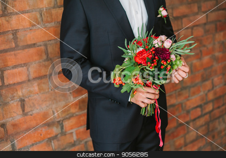 To use this stock image in your creative project, please select the size you need over to the right and click the "Add to Cart" button.
Your downloaded image will come with the Cutcaster watermark removed so don’t worry about the watermark you see on this page. elegant man dressed in a modern black suit and white shirt holding in hand a wedding flowers bouquet from red carnation. Close up color vertical image of male hands holding bunch of bright flowers. stock photo, the elegant man dressed in a modern black suit and white shirt holding in hand a wedding flowers bouquet from red carnation on a brick wall background. date, engagement, romantic, event concept. by Dmitry