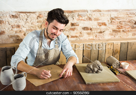 To use this stock image in your creative project, please select the size you need over to the right and click the "Add to Cart" button.
Your downloaded image will come with the Cutcaster watermark removed so don’t worry about the watermark you see on this page. potter, workshop, artisan tools, ceramics art concept - smiling young male man working on the design of future products, a ceramist sitting behind desk with tools, fireclay and finished jugs. stock photo, potter, workshop, artisan tools, ceramics art concept - smiling young male man working on the design of future products, a ceramist sitting behind desk with tools, fireclay and finished jugs by Dmitry
