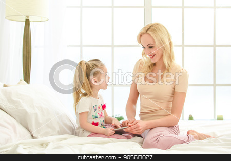 To use this stock image in your creative project, please select the size you need over to the right and click the "Add to Cart" button.
Your downloaded image will come with the Cutcaster watermark removed so don’t worry about the watermark you see on this page. Young mother and daughter morning on bed indoors stock photo, Young mother and daughter morning on bed at home using digital device by Dmytro Sidelnikov