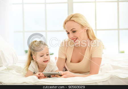 To use this stock image in your creative project, please select the size you need over to the right and click the "Add to Cart" button.
Your downloaded image will come with the Cutcaster watermark removed so don’t worry about the watermark you see on this page. Young mother and daughter morning on bed indoors stock photo, Young mother and daughter morning on bed at home using digital device by Dmytro Sidelnikov
