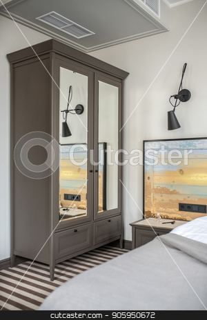 To use this stock image in your creative project, please select the size you need over to the right and click the "Add to Cart" button.
Your downloaded image will come with the Cutcaster watermark removed so don’t worry about the watermark you see on this page. Stylish hotel room stock photo, Nice hotel room with light walls and a striped floor. There is a bed with a colorful wooden bedhead, dark gray wardrobe with mirrors, nightstand with accessories, black lamp on the wall. Vertical. by bezikus